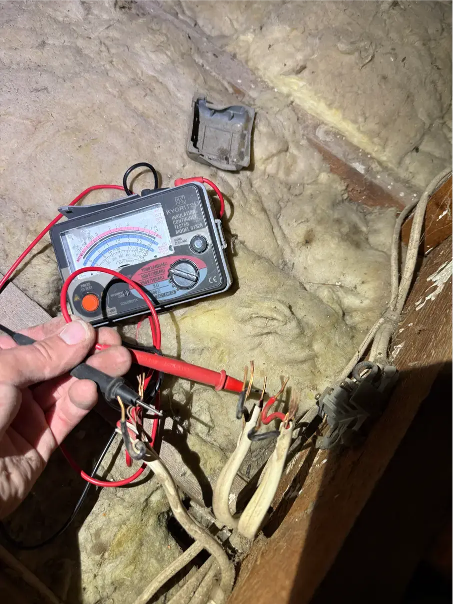 testing damaged wiring in front of insulation