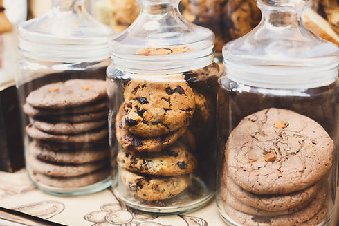 Desserts choice. Cookies and biscuits in glass jars on counter bar for sale. Chocolate dro