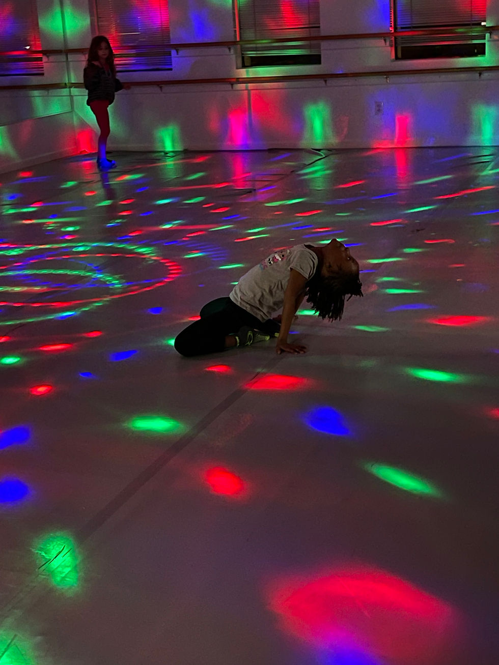 A dancer posing in a dance studio with fun disco lights on them during a kids dance birthday.