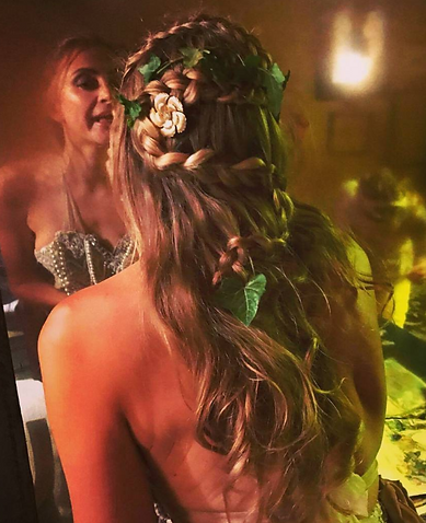 Woman with long, braided boho wedding hair adorned with ivy and floral accessories, styled for a fantasy or woodland-inspired
