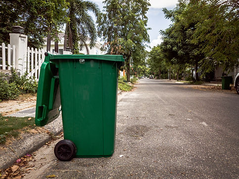 Opened big empty green plastic trash garbage bin in front of the modern house with green t