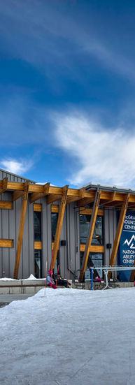 The building sits between a parking lot and open space for people to play in the snow.