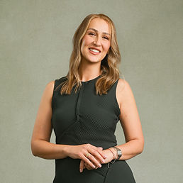 Smiling blonde woman in a black dress posing against a plain background