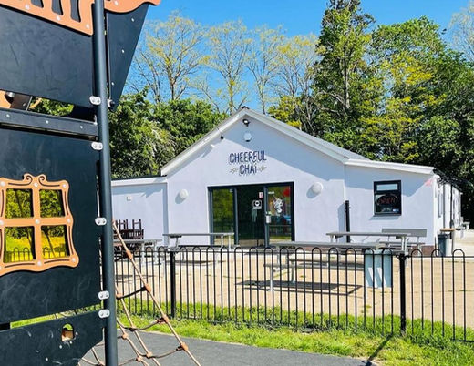 White CHEBEZ CAFE building stands next to a children's playground on a sunny day.