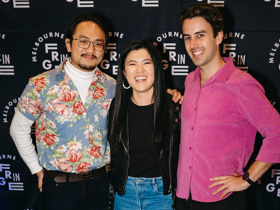 Three people smiling in front of a black and white media wall with the Melbourne Fringe logo.