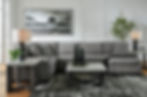 Gray sectional sofa with pillows, art, and two square tables.