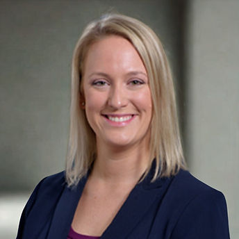 Professional headshot of a smiling blonde woman in a blue jacket.