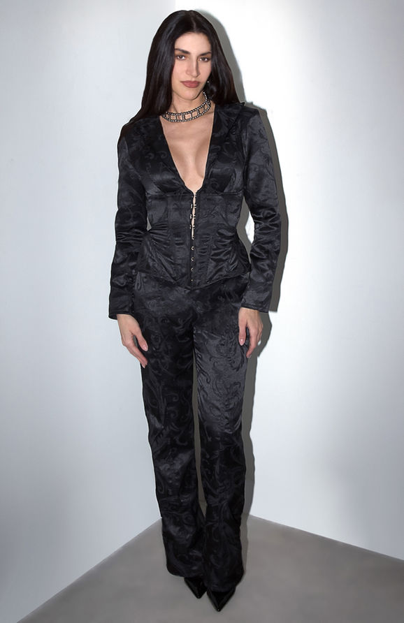 Model in a black jacquard blazer with corset-style front and matching tailored pants.