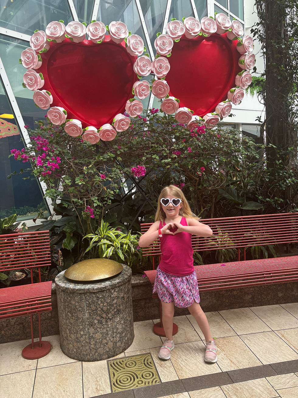 Girl, Jordyn, in front of hearts making a heart with her hands