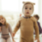 Modelfoto, Kleinkind trägt unisex Baby langarm Body und Hose in camel brown mit süßer Babyhaube, Design Alpenzauber