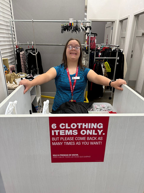 Woman at the counter of a clothing store, smiling.