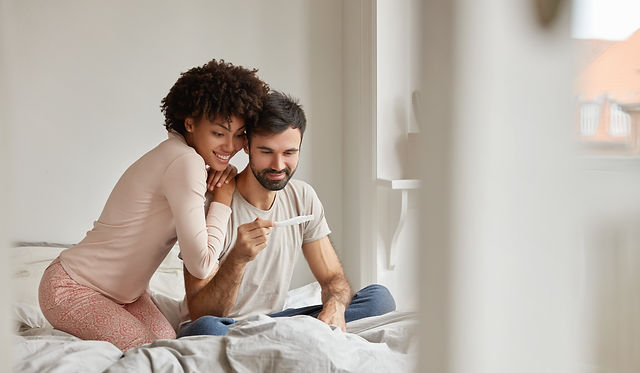 Blij stel kijkt samen naar een positieve zwangerschapstest, symboliserend het begin van hun reis met Duurzame Geboortebegeleiding en Doula Diensten in Zaandam.