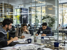 Students collaborate in modern study space with finance admission text