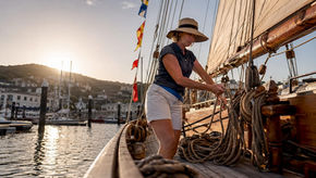 Woman adjusting sail on historic schooner deck