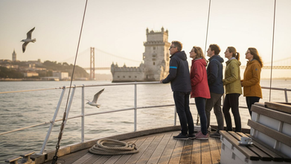 Tourists on sailboat viewing Lisbon coastline at sunset