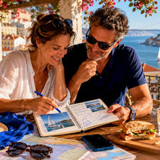 Couple reviewing cruise brochures near Lisbon waterfront