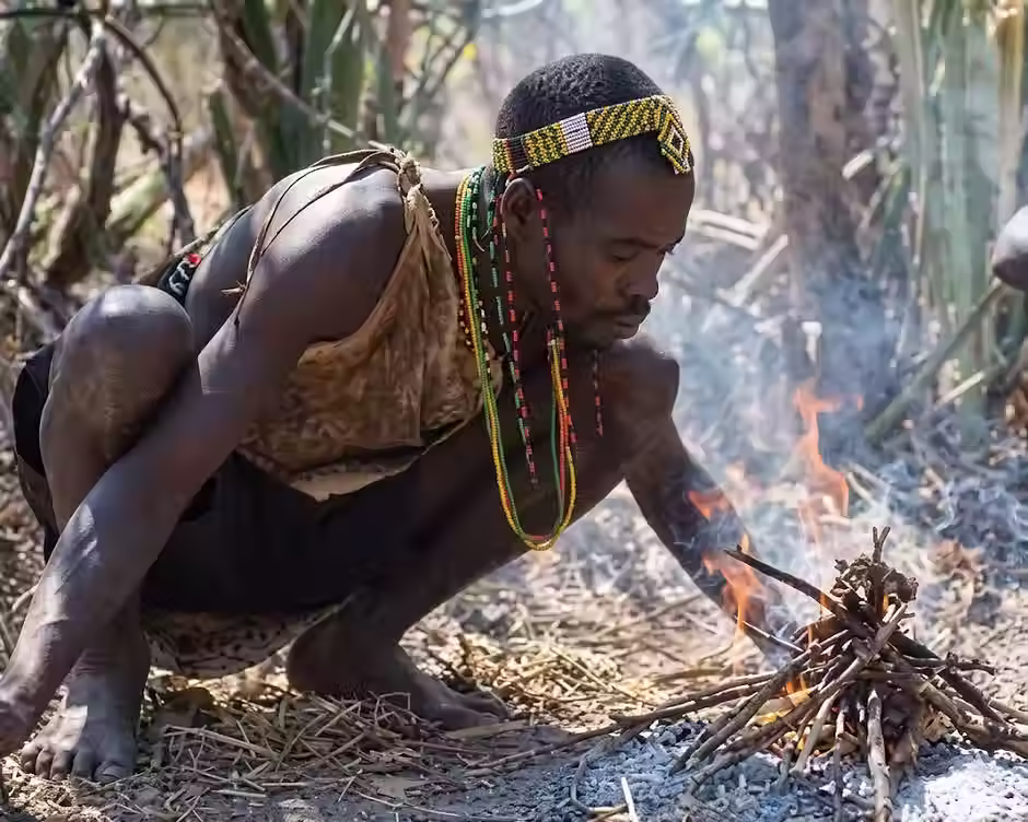 een man die squat op de grond terwijl hij vuur maakt