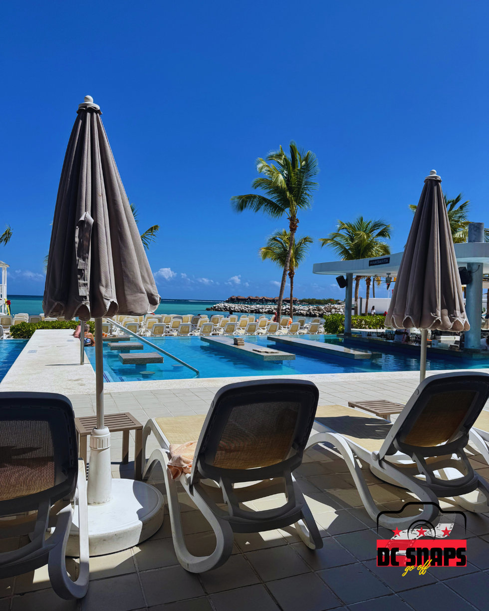 Sun loungers and umbrellas overlooking a pristine beach and turquoise sea, captured on a bright tropical day.