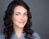 a woman with curly hair and blue eyes smiles for the camera