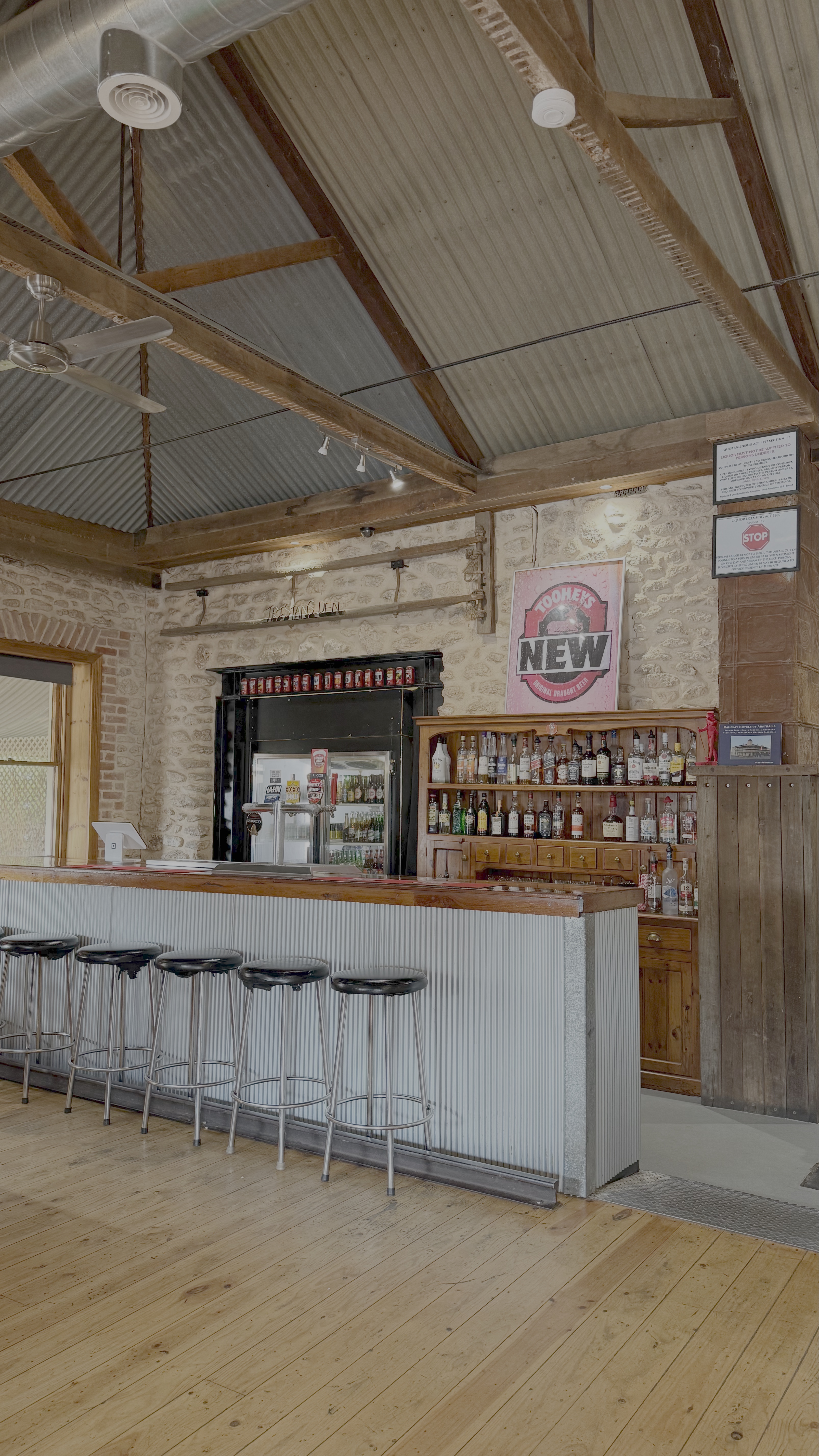 The front bar at the Gungellan Hotel, with corrugated iron, a stone fireplace and bar stools