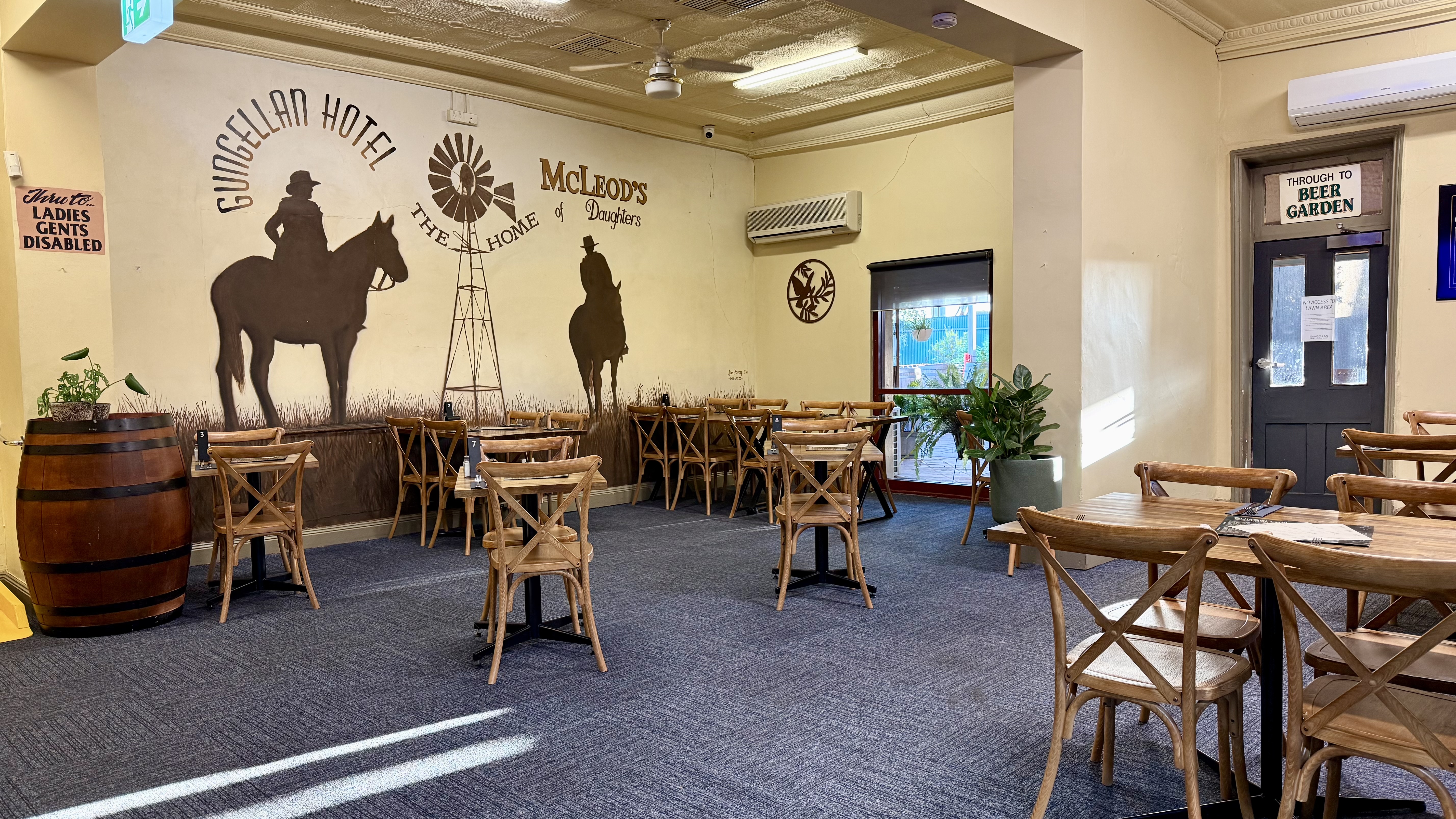 Mural of the Gungellan Hotel and McLeod's Daughters, with cowboy silhouettes on horseback and a windmill, painted on the dining room wall