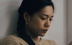 woman leaning back on white wall and usi
