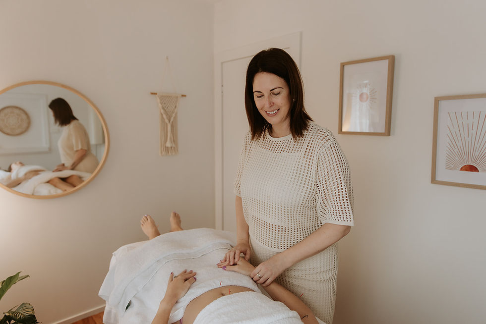 Angela Marshall, Brisbane Acupuncturist, performs acupuncture on a woman lying on a table. Room has calming decor with framed art and a round mirror. Relaxed mood.