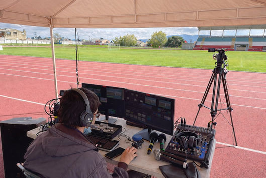 Puesto de transmisión deportiva en vivo en pista atlética con cámara fija y mezcla profesional