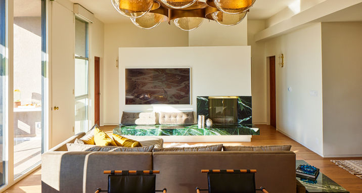 The rich warmth of the green marble fireplace and matching floating bench mirrors the custom sofa with floating side table.