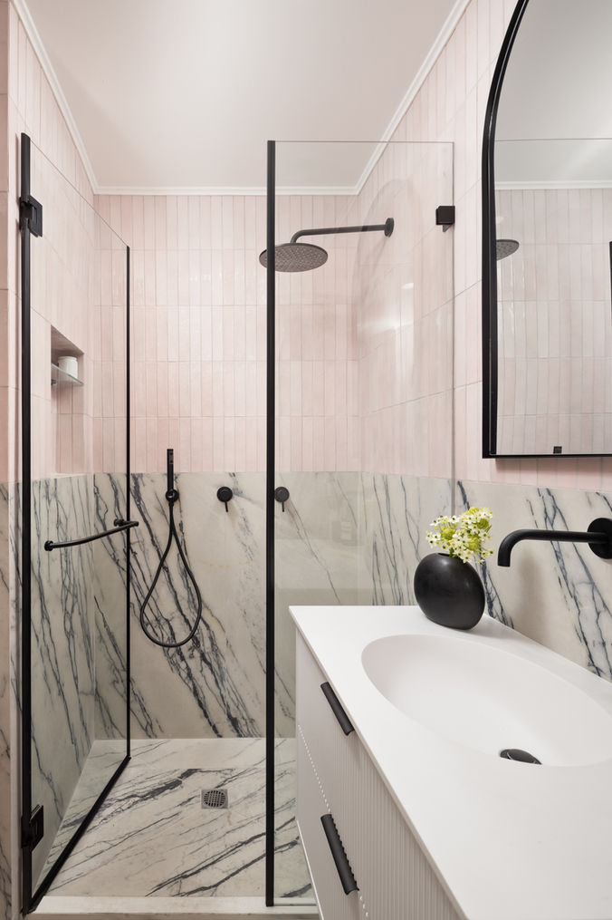 Modern bathroom with pink tiles, shower, sink and mirror. Alyssa Magid Interiors