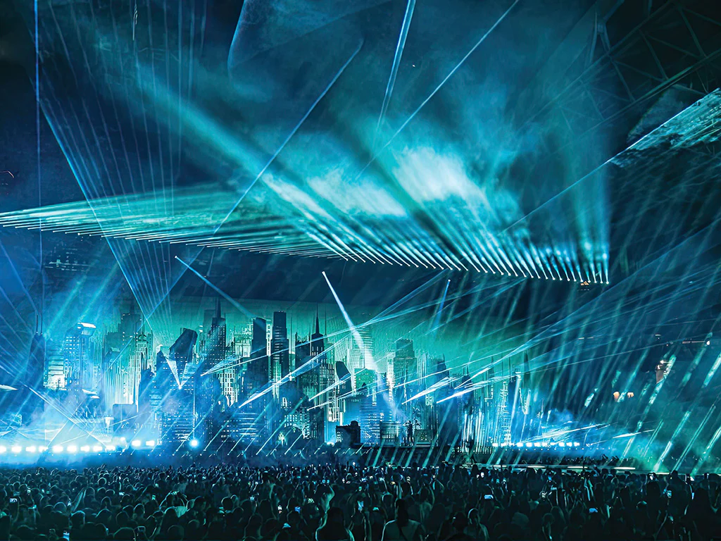 main stage showing the city landscape and beams of lights with a crowd