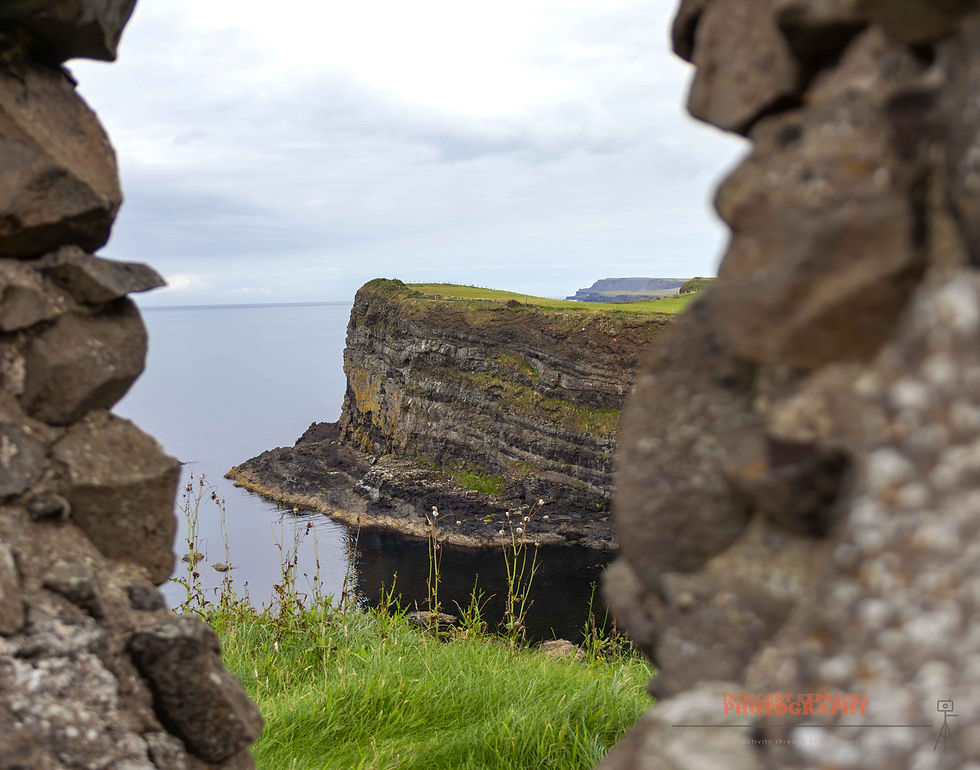 Stone frame reveals a cliff peninsula over calm ocean, viewed through a rock opening. Moody sky with distant land. Text: Innocent Exposure Photography.
