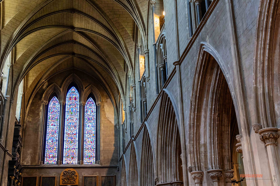 Gothic cathedral interior with stained glass windows, vaulted ceilings, and stone arches. Soft light illuminates intricate details.