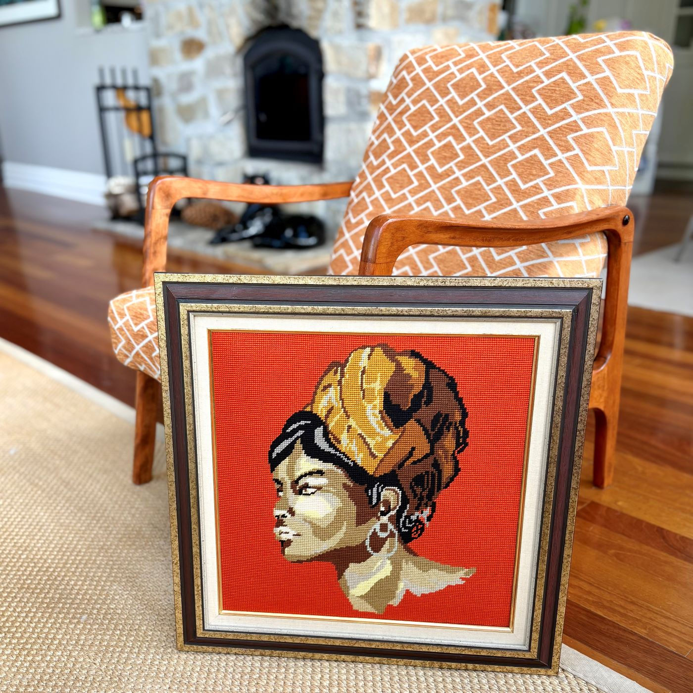 Broderie artisanale vintage posée au sol – Portrait de femme au turban orange sur fond rouge, encadrement bois doré