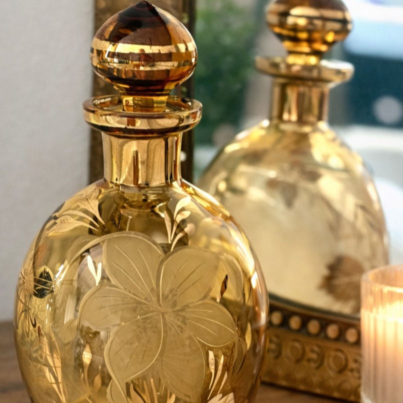 Flacon vintage en verre ambré gravé de motifs floraux, style bohème, posé sur une coiffeuse avec miroir