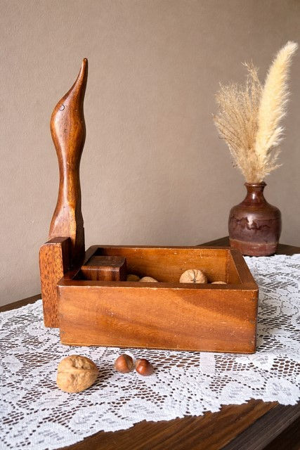 Miniature : Casse-noix vintage en bois en forme de canard avec compartiment à noix, posé sur une table avec nappe en dentelle
