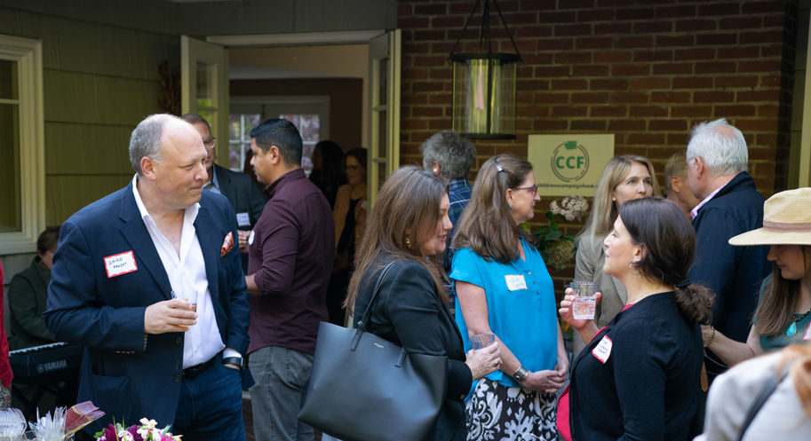 Guests, candidates, and board members mingle outside on a deck
