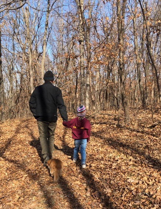 The author walking in the woods, holding the hand of his young grand-neice