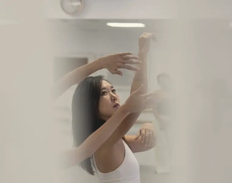 Cathy Lee moving with outstretched arms in a light-filled studio