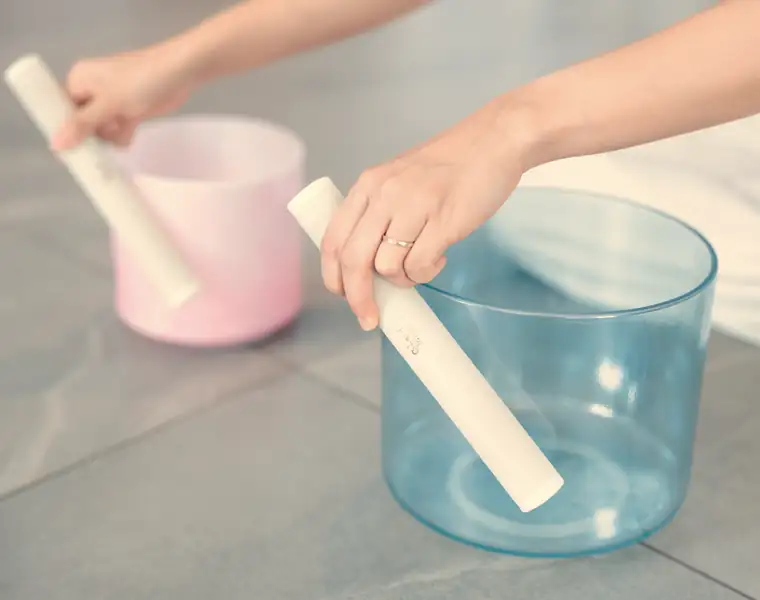 Hands playing pink and blue crystal singing bowls