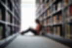 Woman reading by bookshelves