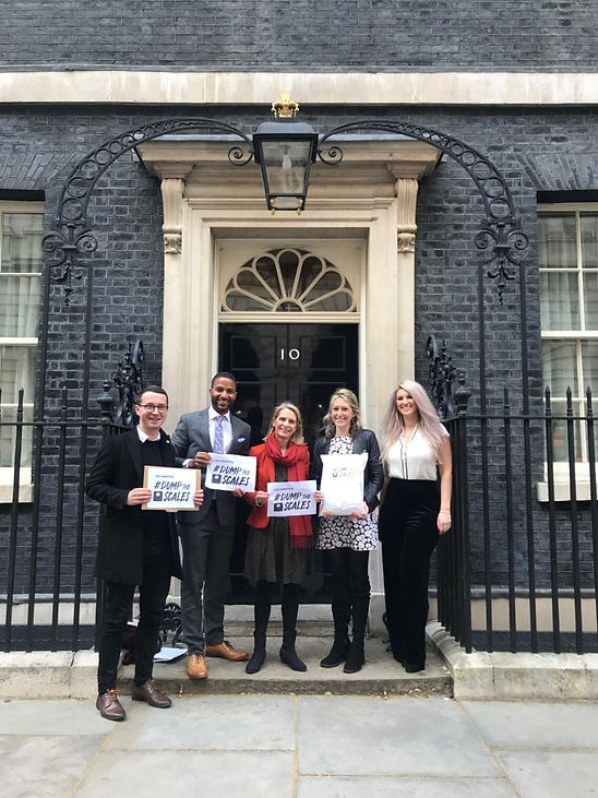 A number of Dump the Scales campaigners standing outside 10 Downing Street holding Dump the Scales signs.