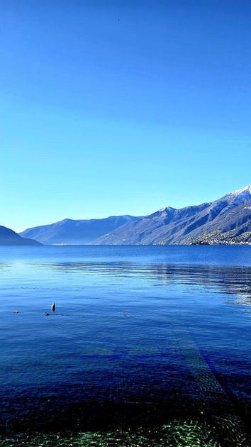 Lago tranquillo con montagne innevate e cielo sereno riflettuto nell'acqua.
