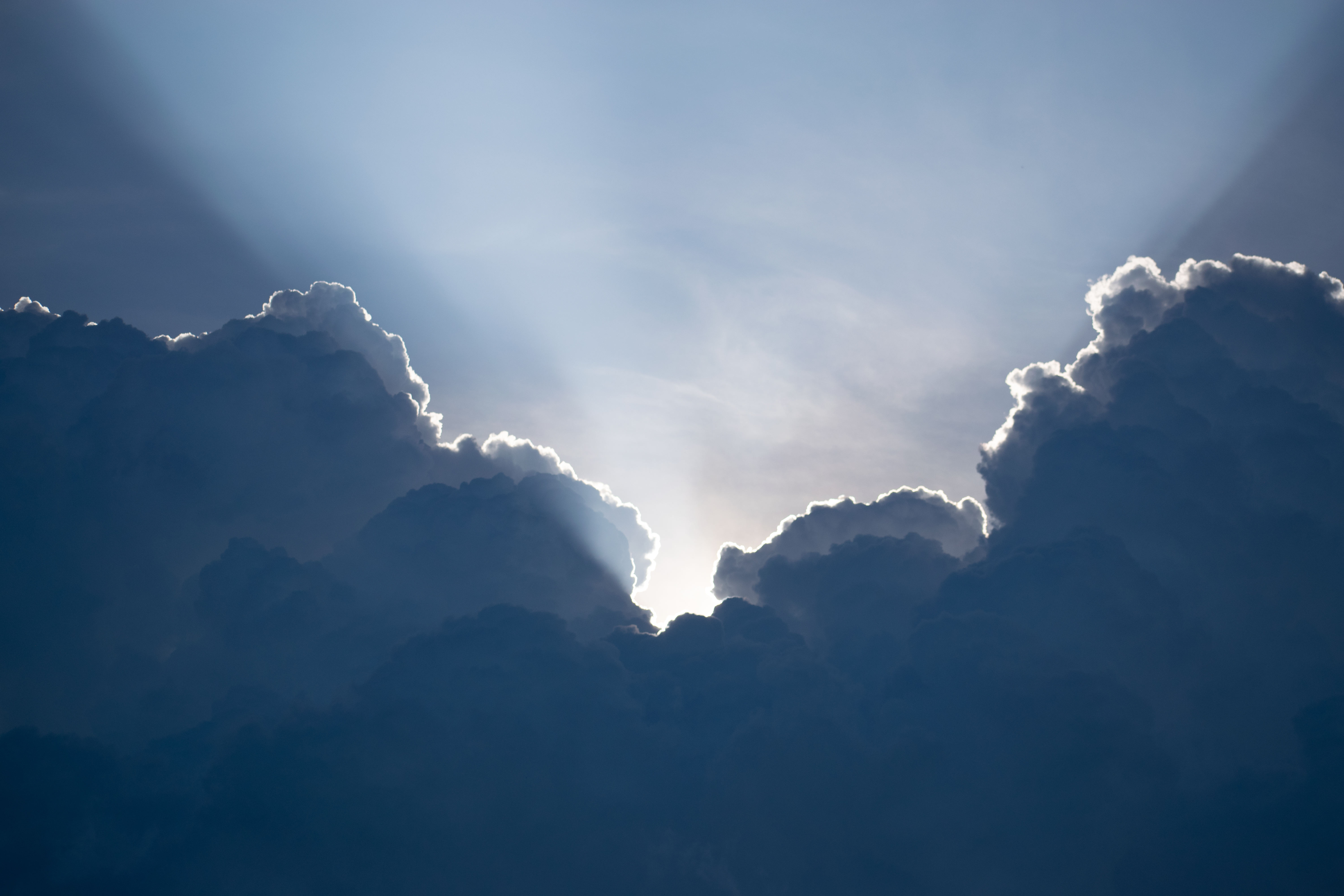 Thick clouds shroud the sun, light pouring through. 