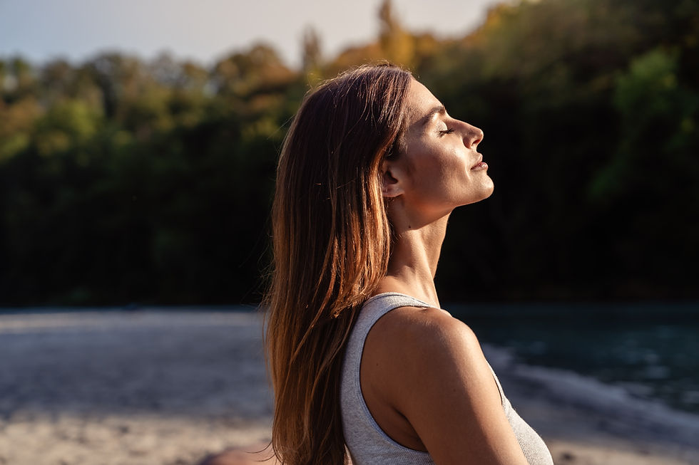 Young woman with long hair enjoying sun with closed eyes getting natural vitamin D outdoor