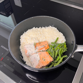 Lachs, Reis und grüne Bohne auf dem Herd in der Pfanne