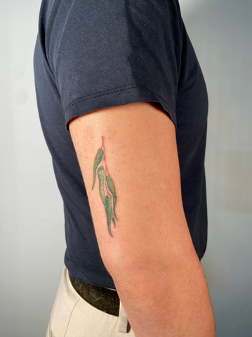 Person's arm with green leaf tattoo