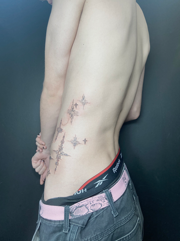 Person's side tattoo: sparkling stars design