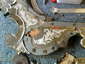 close-up of dismantled etched Victorian mirror during restoration showing floral engraving and original silvering
