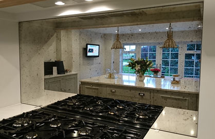 Modern kitchen featuring a made-to-measure antique mirror splashback above a range cooker, designed and installed by Mirror Works.